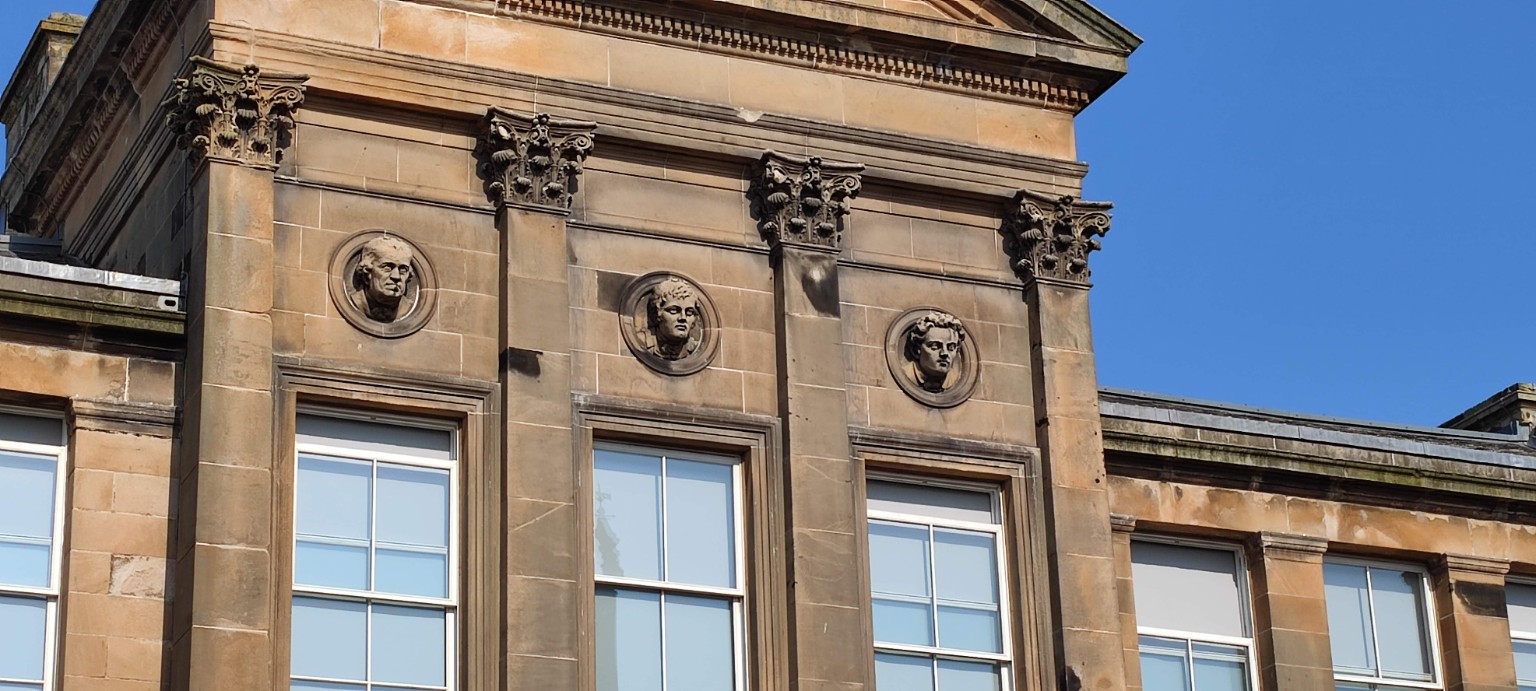 Carved stone faces high on a building in Ayr